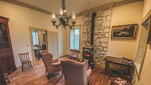 A cozy living room with a stone wall, wooden furniture, and a fireplace. - Funks Inn, a post civil war era home restored as it was in 1870. (Bloomsdale)