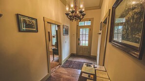 A hallway with wooden flooring, a chandelier, framed pictures, and a door with glass panels. - Funks Inn, a post civil war era home restored as it was in 1870. (Bloomsdale)