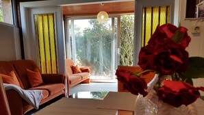 A modern living room with a sofa, a coffee table, and a vase of red roses.