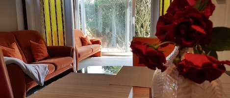 A modern living room with a sofa, a coffee table, and a vase of red roses.