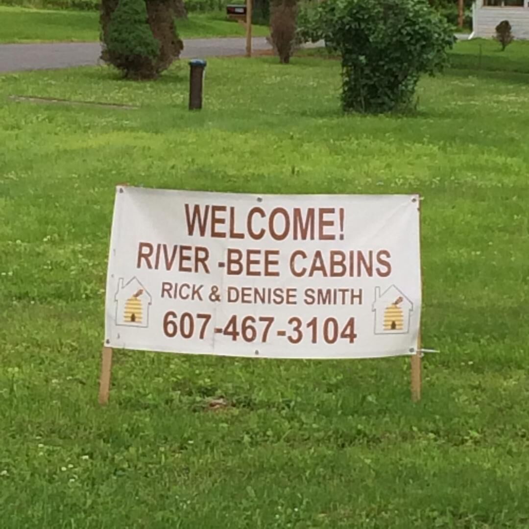 A welcome sign for River-Bee Cabins by Rick & Denise Smith, including a phone number.