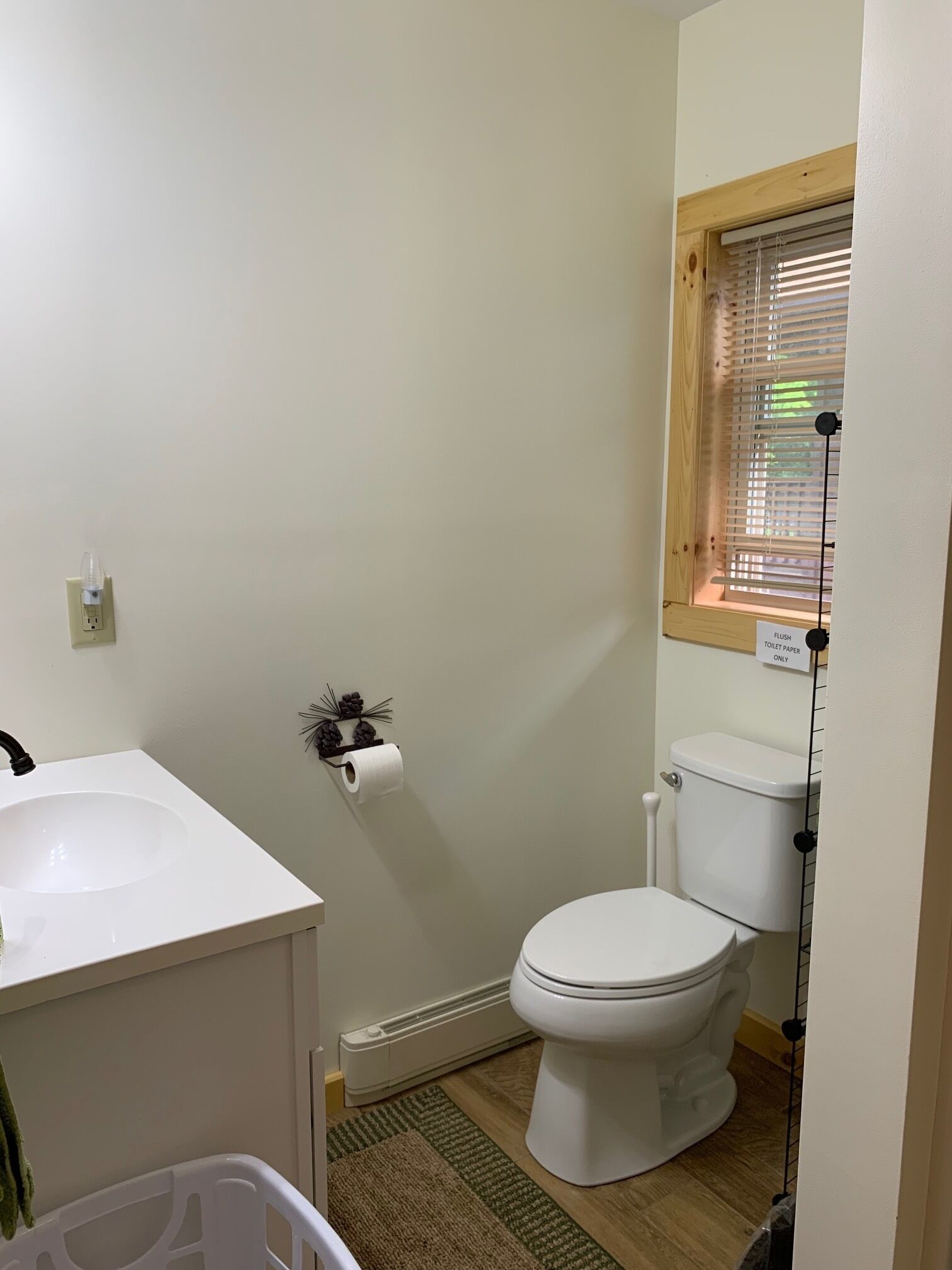 A small bathroom with a white sink, toilet, and a window with blinds.
