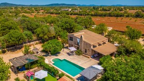 Una villa con piscina, mobiliario exterior y un edificio de piedra.