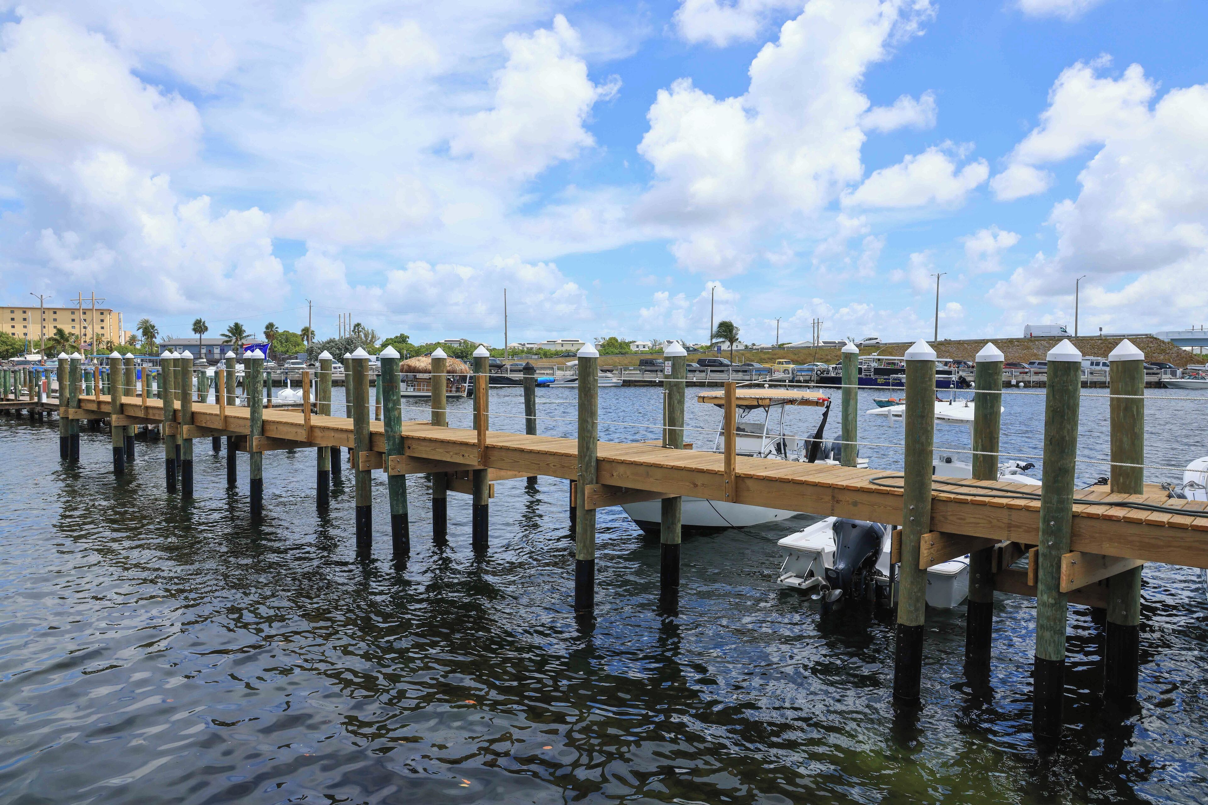 A wooden pier extending into calm water with boats docked nearby.