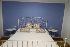 A bed with a white metal frame, floral-patterned pillows, and two small round tables with lamps. - Zone 23 Home - wonderful apartment just a step away from the beach (Poris de Abona)