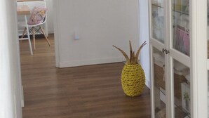 Un pasillo con suelo de madera, una puerta blanca y un aparador de vidrio con estantes.
