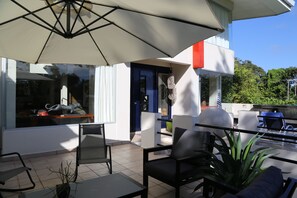Un patio al aire libre con mesa, sillas y un paraguas grande.