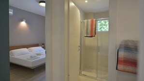 Una habitación de hotel moderna con cama, ducha y puerta de cristal.