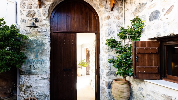 Un edificio de piedra con una puerta de madera y plantas en macetas.