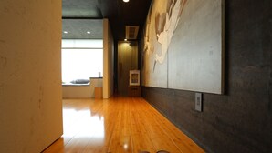 Un couloir doté d’un plancher en bois, d’une grande fresque murale et d’une porte donnant sur une autre pièce.