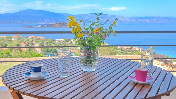 Une table en bois avec un verre d’eau, une tasse et un vase rempli de fleurs.