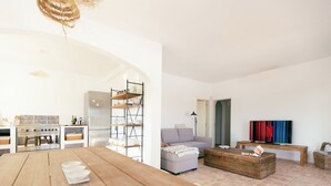 A spacious living area with a wooden dining table, a grey sofa, a wooden coffee table, and a TV on a wooden stand. - Casa La Paz, trendy home of peace. (Faro)