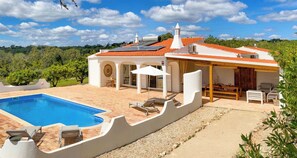 Uma villa com piscina, área de estar ao ar livre e vista para a paisagem ao redor.