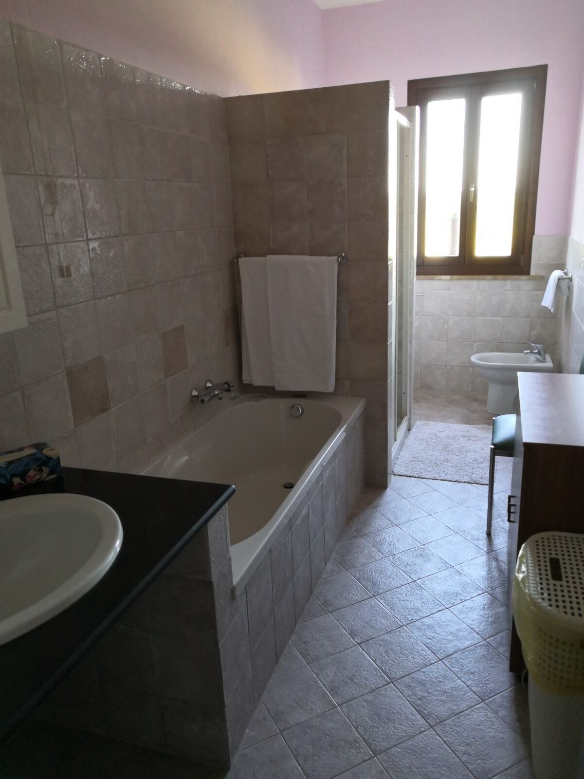 A bathroom with a bathtub, a sink, a toilet, and a window.