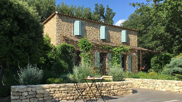 A stone house with a wooden deck and a pool.