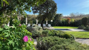 A garden with a pool, surrounded by well-maintained hedges and trees.