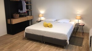 A bedroom with a bed, bedside lamps, a wardrobe, and a hanging shelf.