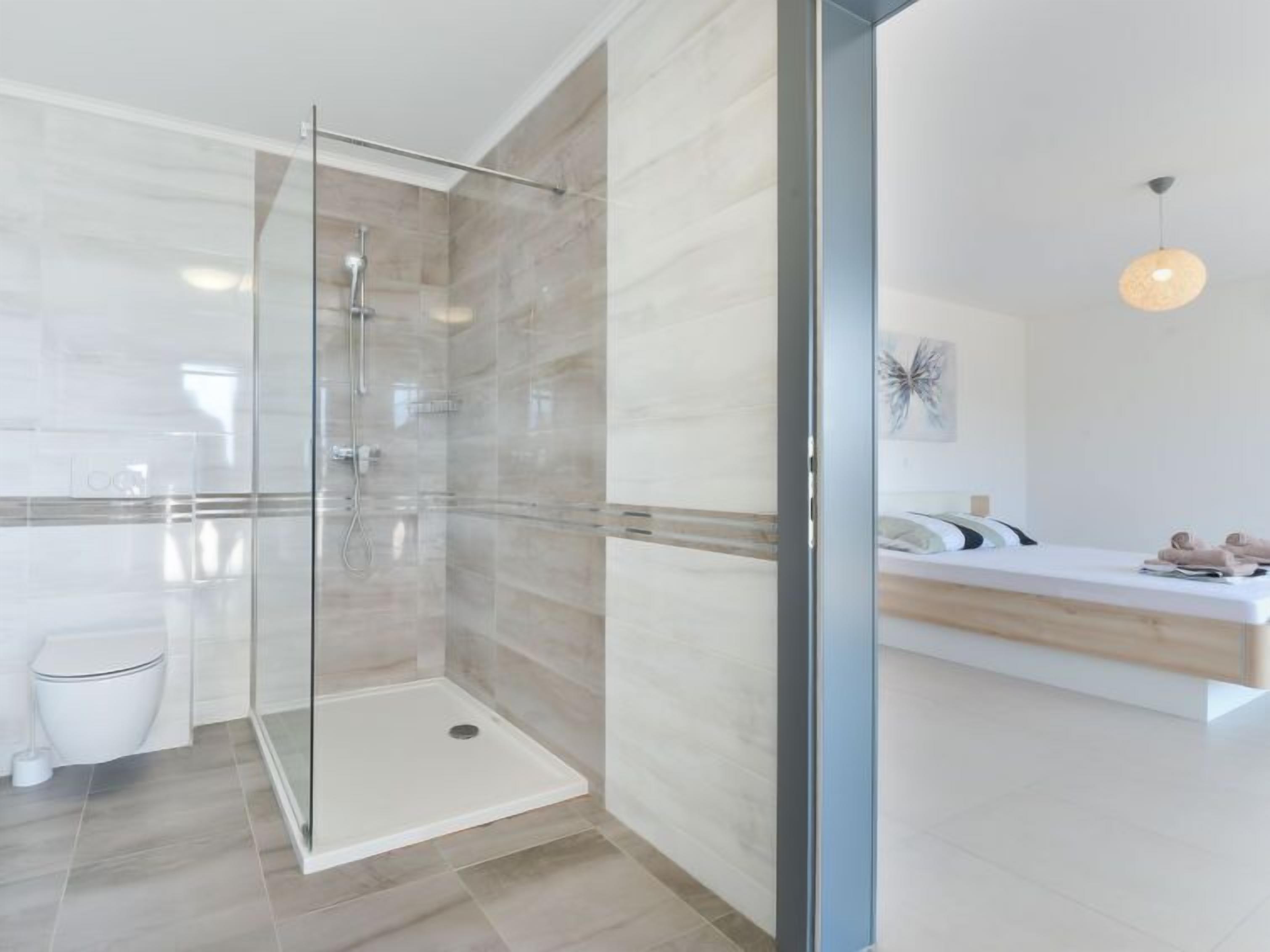A modern bathroom with a glass shower enclosure, a toilet, and a vanity with a sink and countertop.
