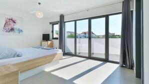 A modern bedroom with a bed, a desk, and a large sliding glass door leading to a balcony. - Vacation home East by Interhome (Vodice/Tribunj)