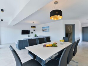 A modern dining area with a white table, black chairs, and a fruit platter. - Vacation home East by Interhome (Vodice/Tribunj)