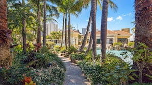 A pathway leading to a pool area surrounded by palm trees and tropical plants. - Chevron Renaissance Ocean View (Surfers Paradise)