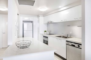 Una cocina moderna con armarios blancos, lavavajillas integrado y refrigerador de acero inoxidable.