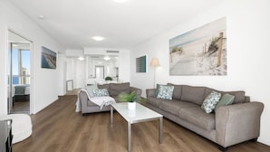 A modern living room with two sofas, a coffee table, and a painting of a beach scene. - Chevron Renaissance Ocean View (Surfers Paradise)