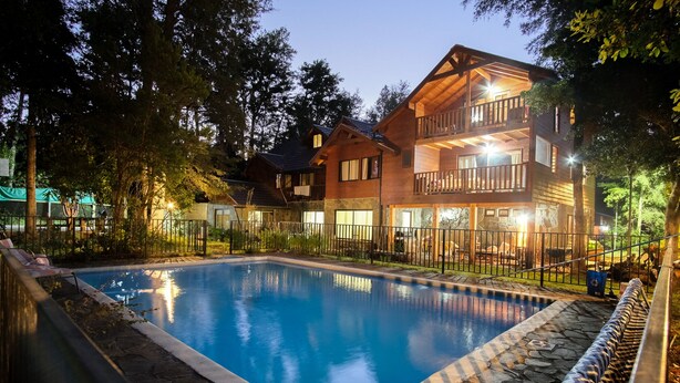 Un edificio de madera de dos pisos con piscina, borde de piedra y patio amurallado.