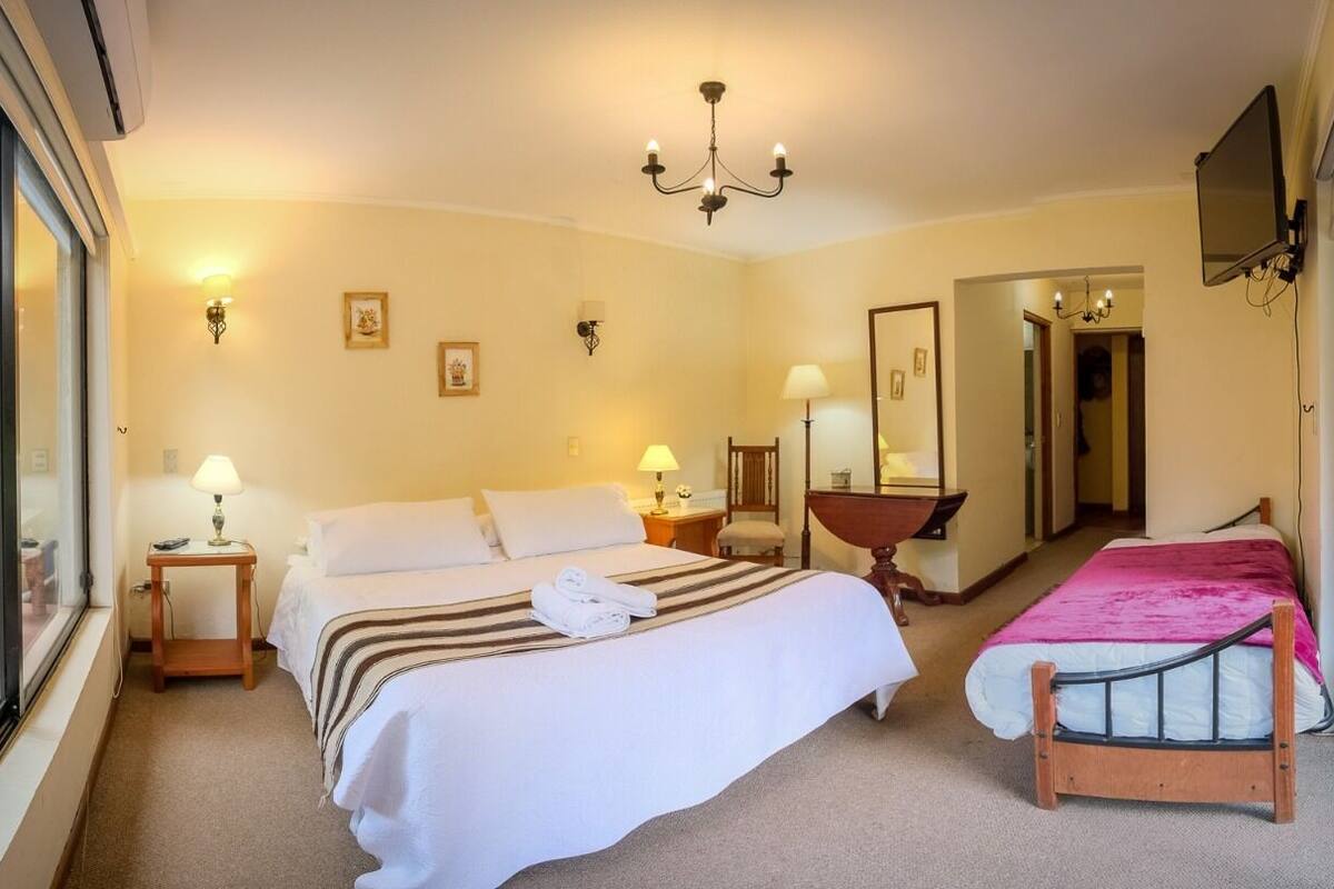 Habitación de hotel con dos camas, un candelabro, un espejo grande y vistas por la ventana.