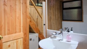 Un baño de madera con lavamanos, espejo y puerta de madera.