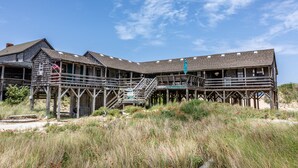 Een houten steigerconstructie met meerdere terrassen en trappen, die uitsteekt in een grasveld met bloemen.