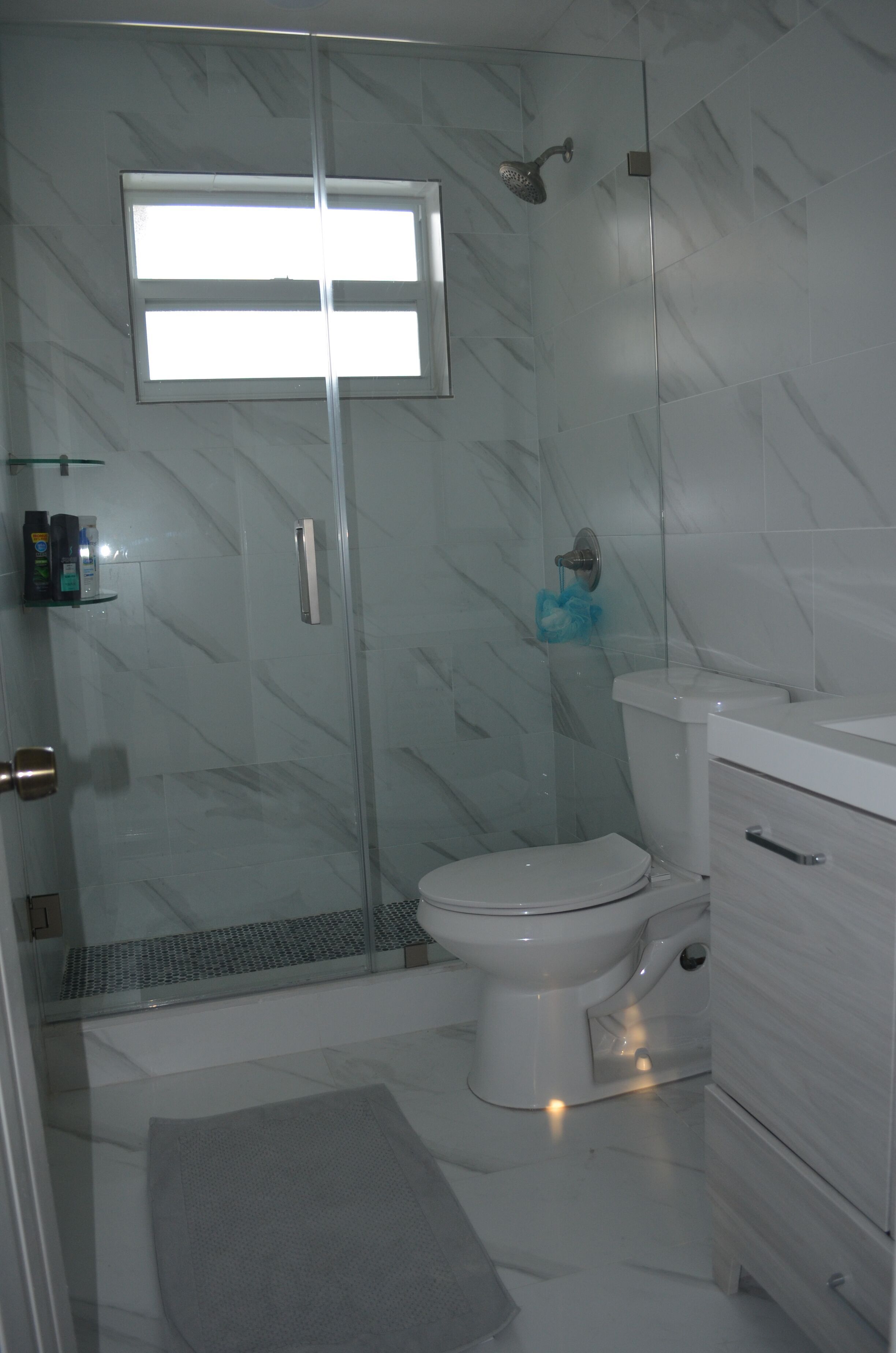 Een moderne badkamer met een douchecabine van glas, een toilet en een witte wastafel.