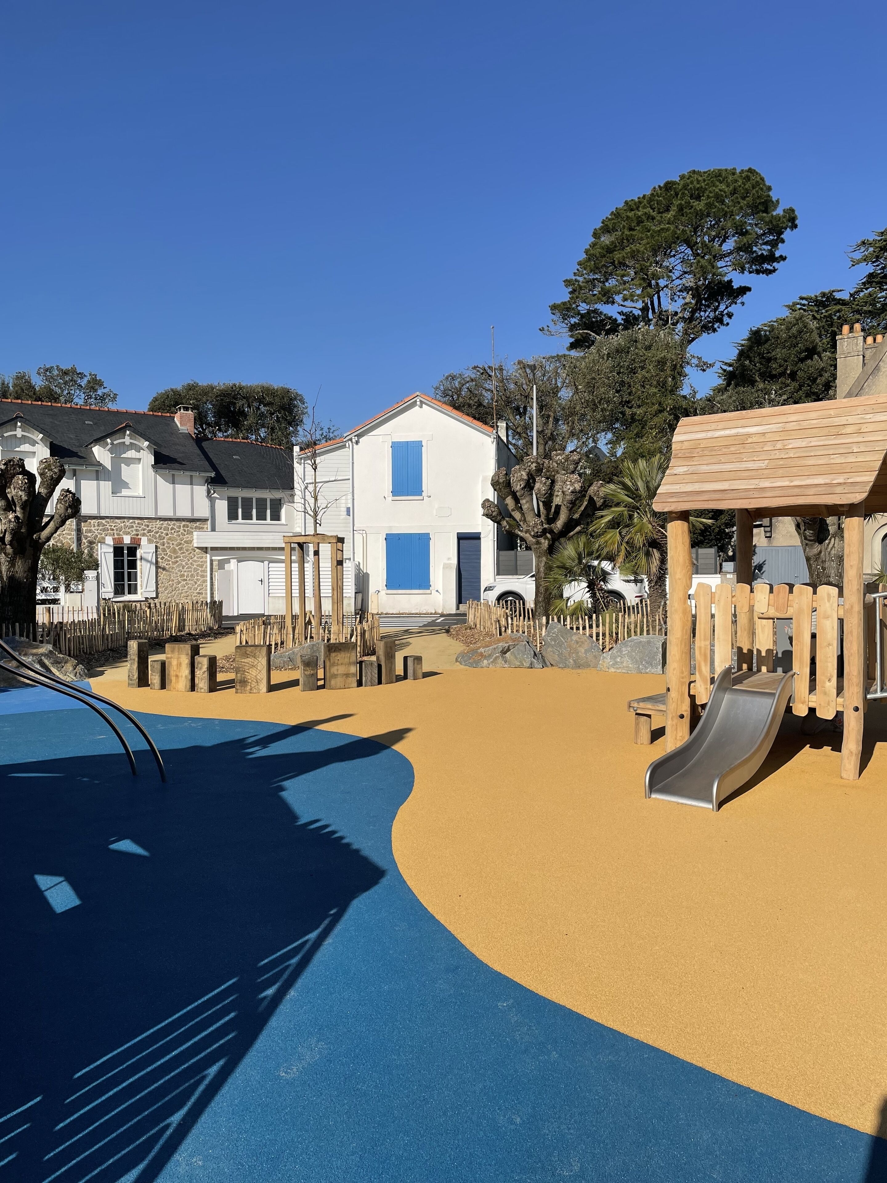 A playground with a slide, sand area, and wooden play structures.