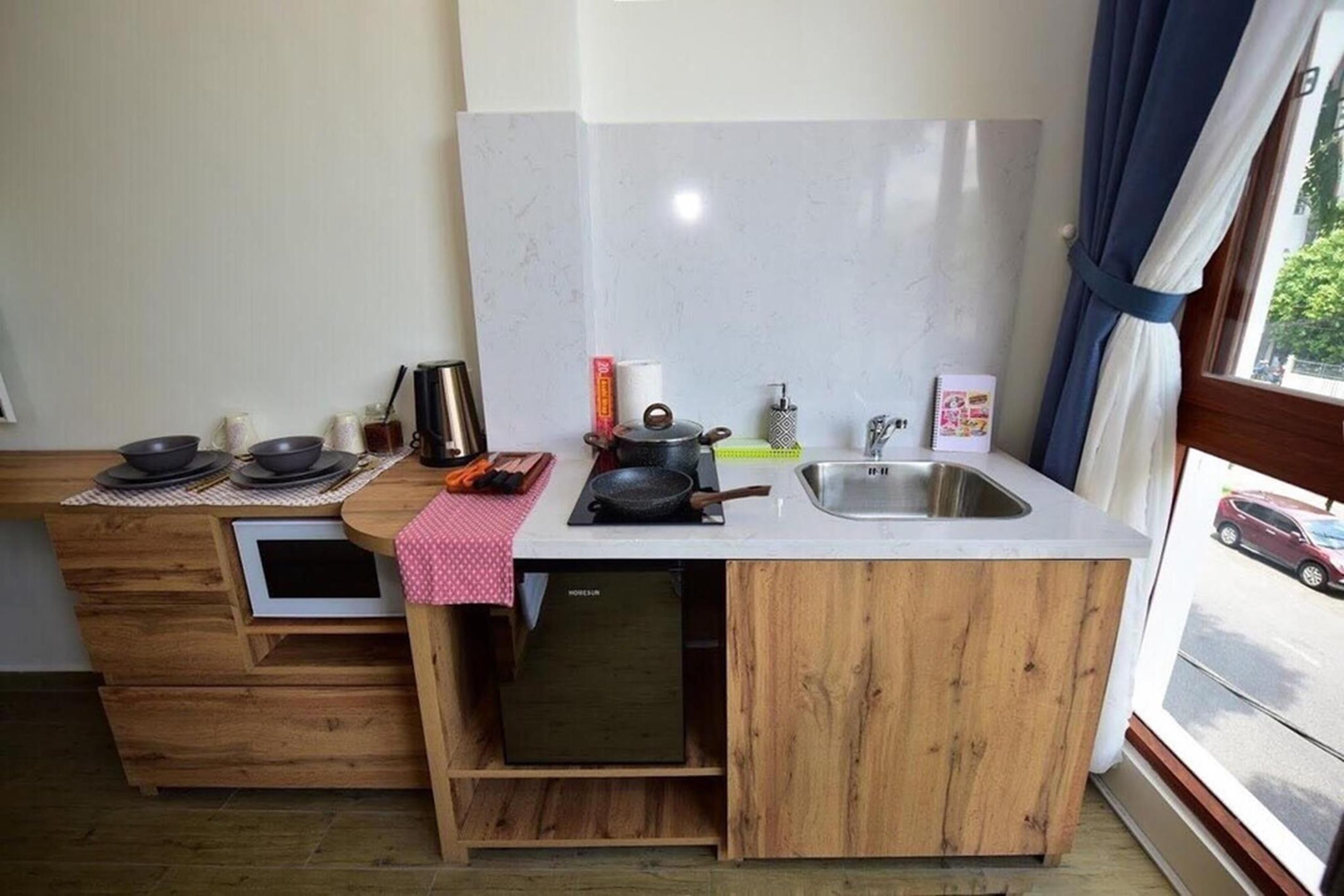 Une cuisine de taille réduite, équipée d’un évier, d’une cuisinière et de placards de rangement.