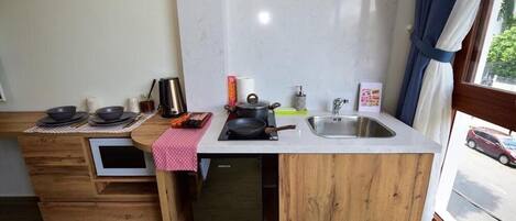 Une cuisine de taille réduite, équipée d’un évier, d’une cuisinière et de placards de rangement.