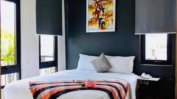 A modern hotel room with a large bed, a bedside table with a phone, and a painting on the wall.