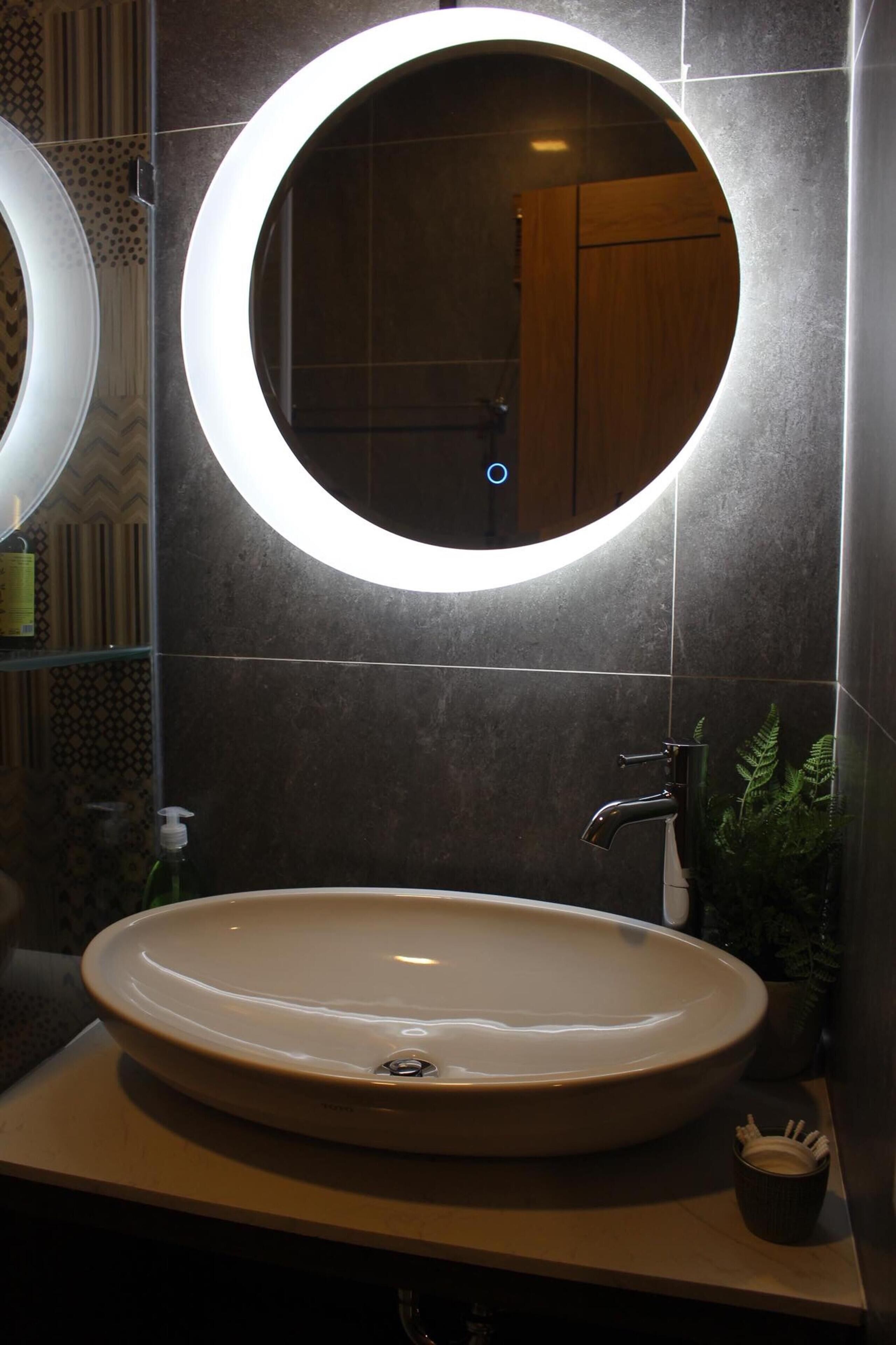 Een badkamer met een ronde spiegel, een wastafel en een kraan.