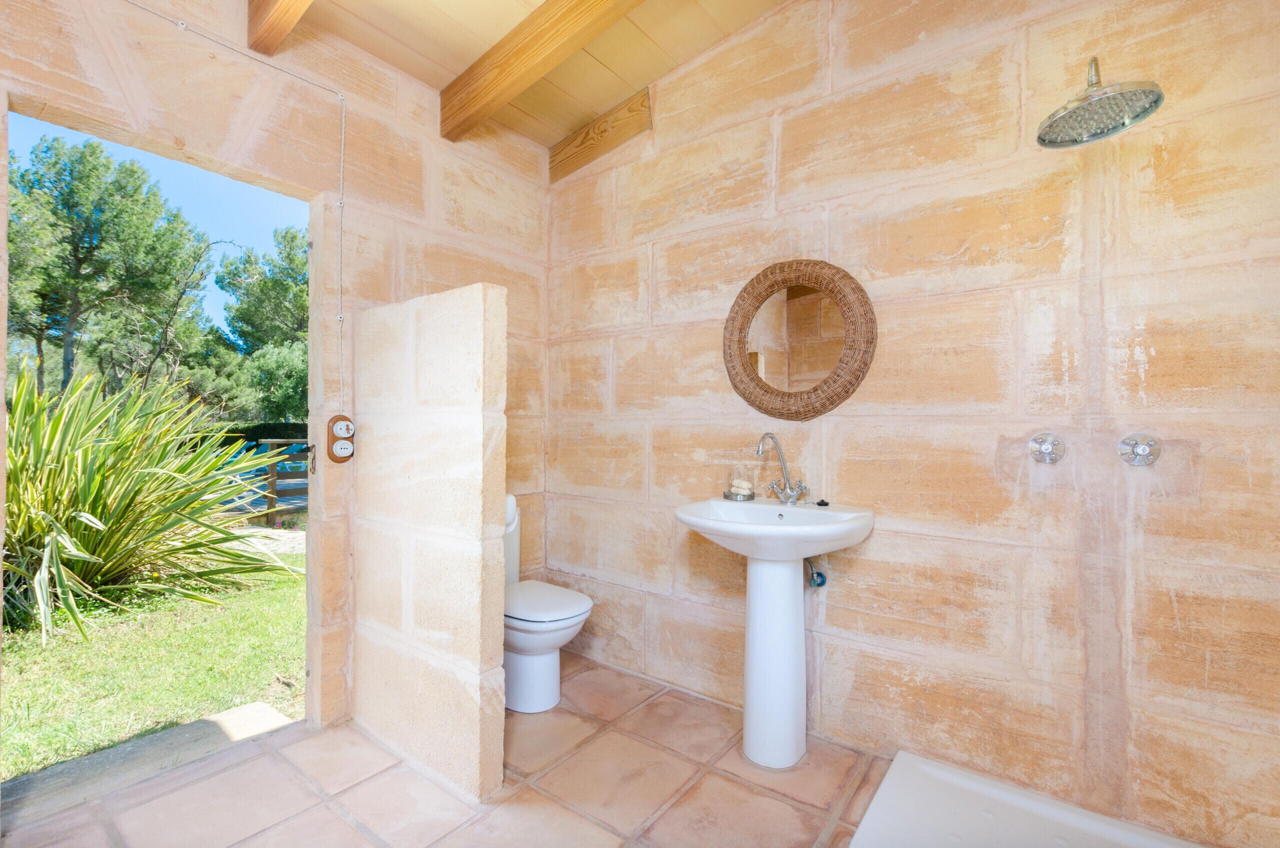 A bathroom with a stone wall, a white sink, a toilet, and a shower.