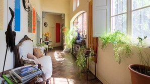 A cozy living room with a wooden floor, a white armchair, and a bookshelf. - Luxury Suite in Renaissance Villa (Grassina)