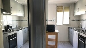 Eine moderne Küche mit weißen Schränken, Edelstahlgeräten und einem Holzschemel.