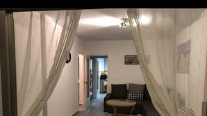 Ein Wohnzimmer mit einer Couch, einem kleinen Tisch und einer Deckenleuchte.