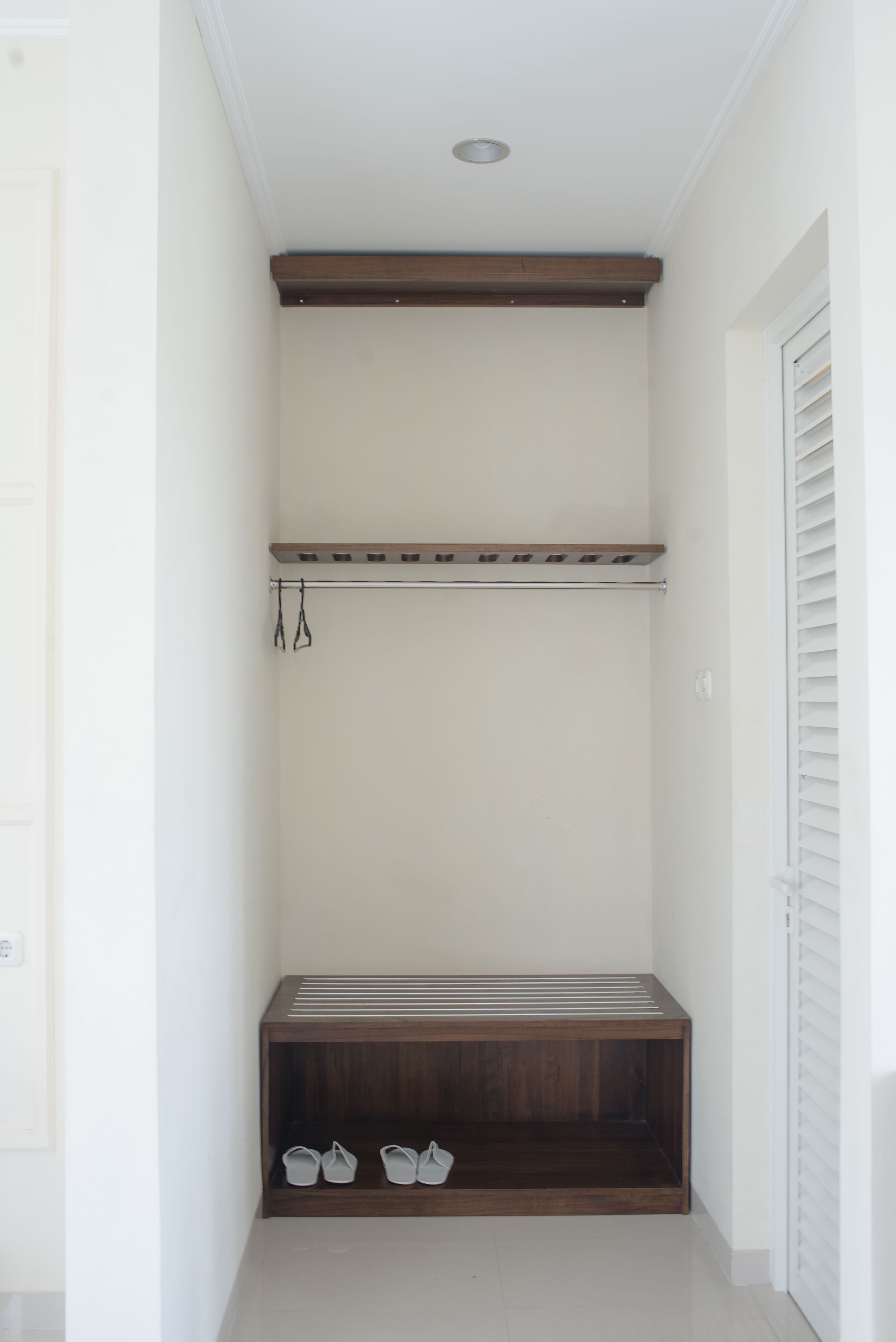 A small, enclosed hallway with a wooden bench and a coat rack.