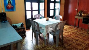 Un comedor con una mesa, sillas, una cafetera y un cuadro en la pared.