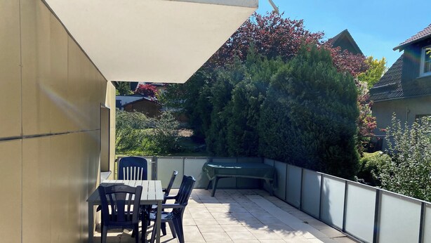 A patio with a table and chairs, a barbecue grill, and a covered area. - Apartment in the city and nature (Kierspe)