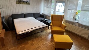 A modern room with a bed, a sofa, a yellow armchair, and a small table. - Apartment in the city and nature (Kierspe)