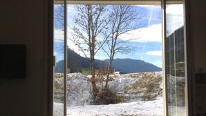 Ein Zimmer mit großem Fenster mit Blick auf eine verschneite Berglandschaft.