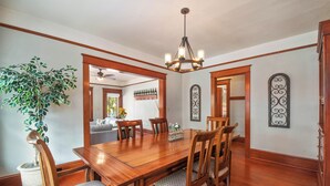 A dining room with a wooden table, chairs, a chandelier, and a potted plant. - Historic 1910 Bungalow & Carriage House • Dog Friendly • 1 Block to Wine & Dine (McMinnville)