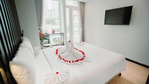 A hotel room with a large bed, a TV mounted on the wall, and a balcony with a view of the city. - Hermes Hotel Nha Trang (Nha Trang)