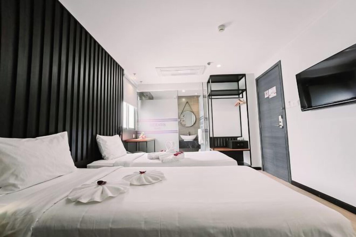 Una habitación de hotel moderna con dos camas, un espejo grande, un televisor y un armario.