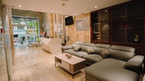 A modern living room with a sectional sofa, a coffee table, and a TV mounted on the wall. - Hermes Hotel Nha Trang (Nha Trang)